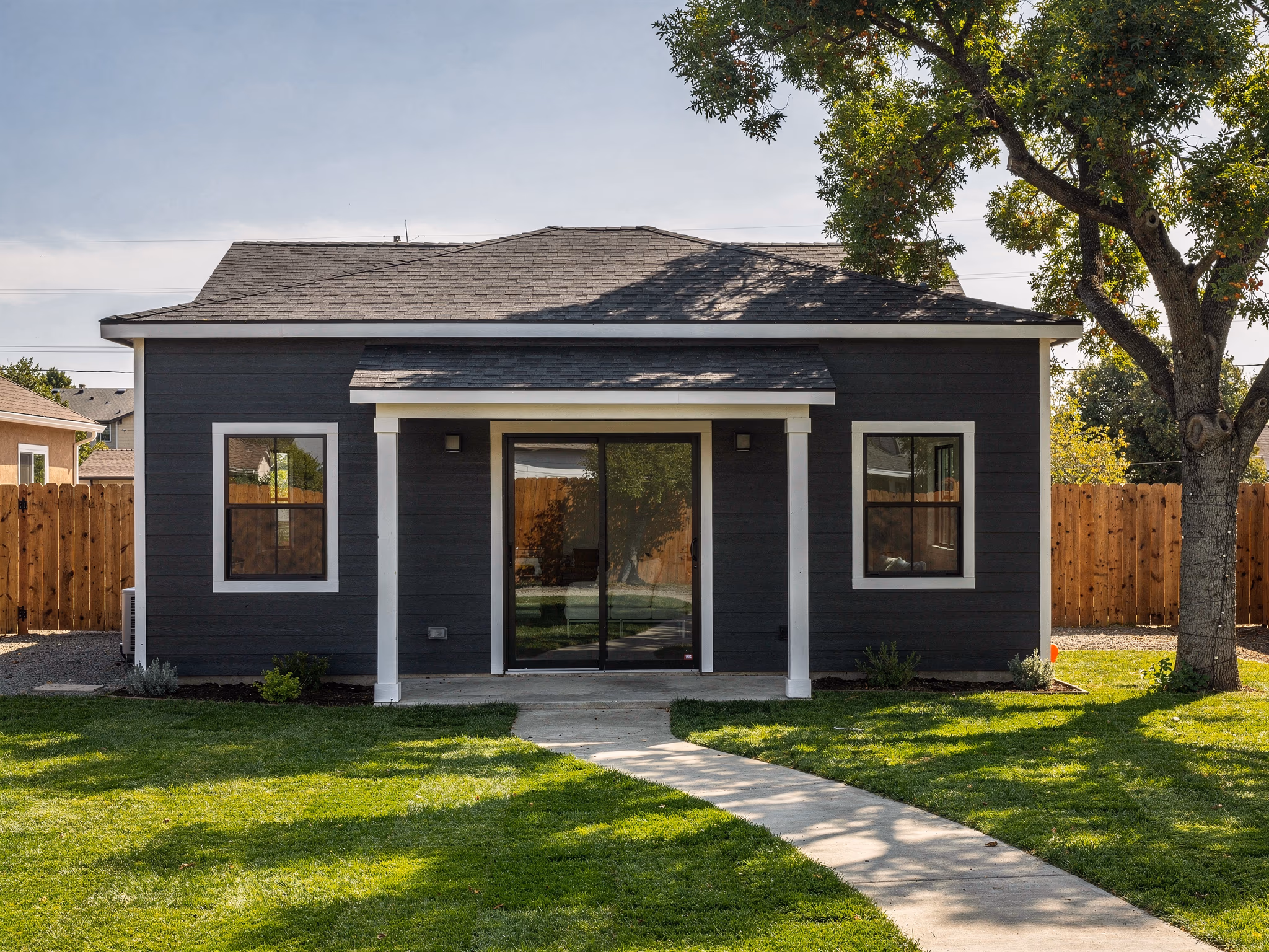 Completed ADU exterior — dark blue siding with white trim in a Sacramento backyard